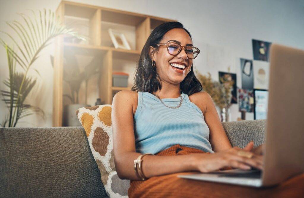 Frau lächelt beim Online-Reservieren eines Wunschkennzeichens auf dem Laptop
